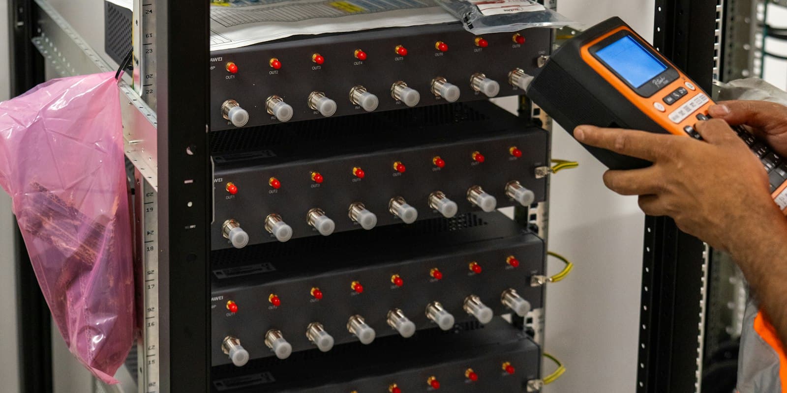 A technician testing telecom equipment in a server rack