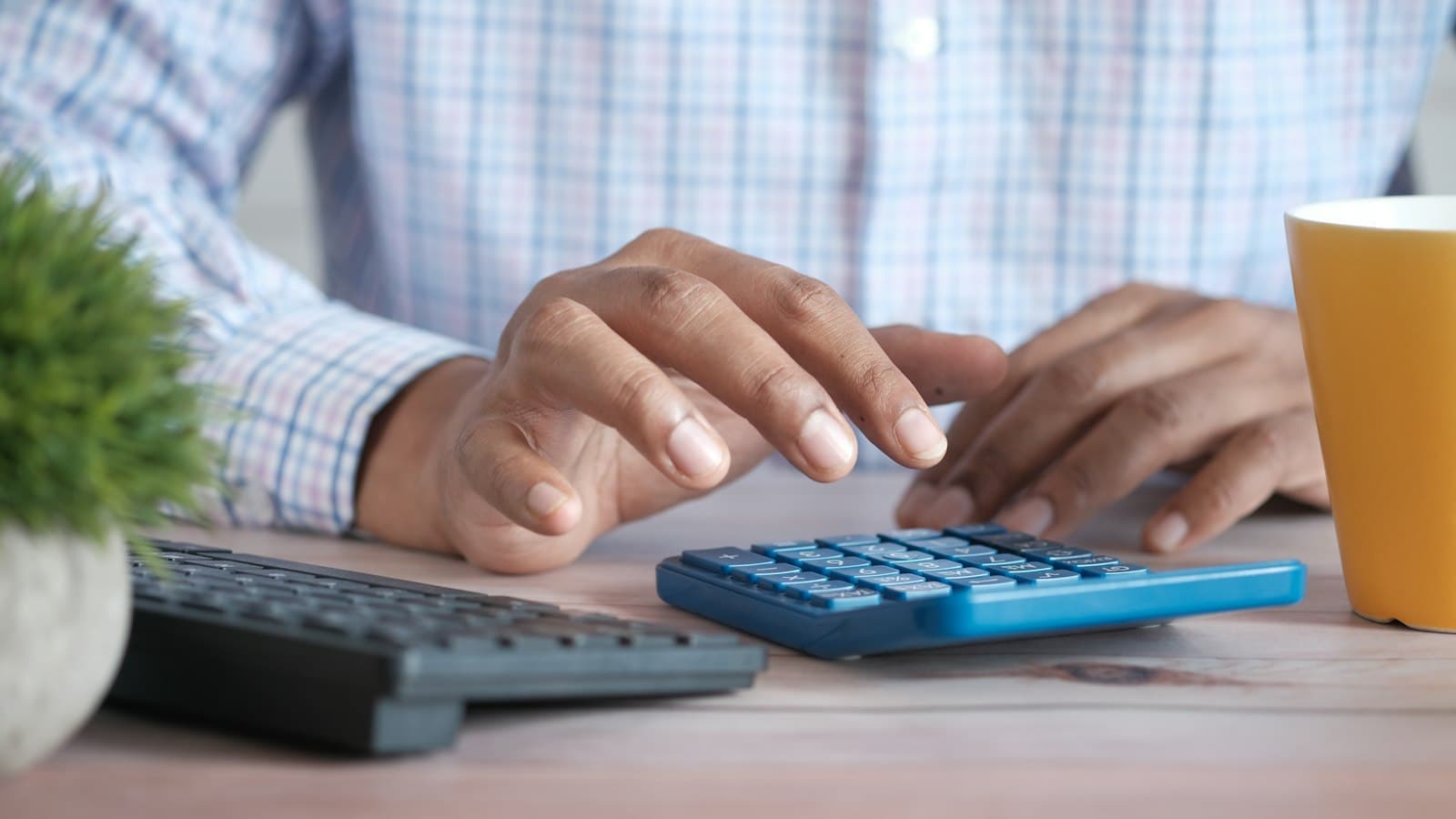 Hands working out figures on a calculator beside a keyboard