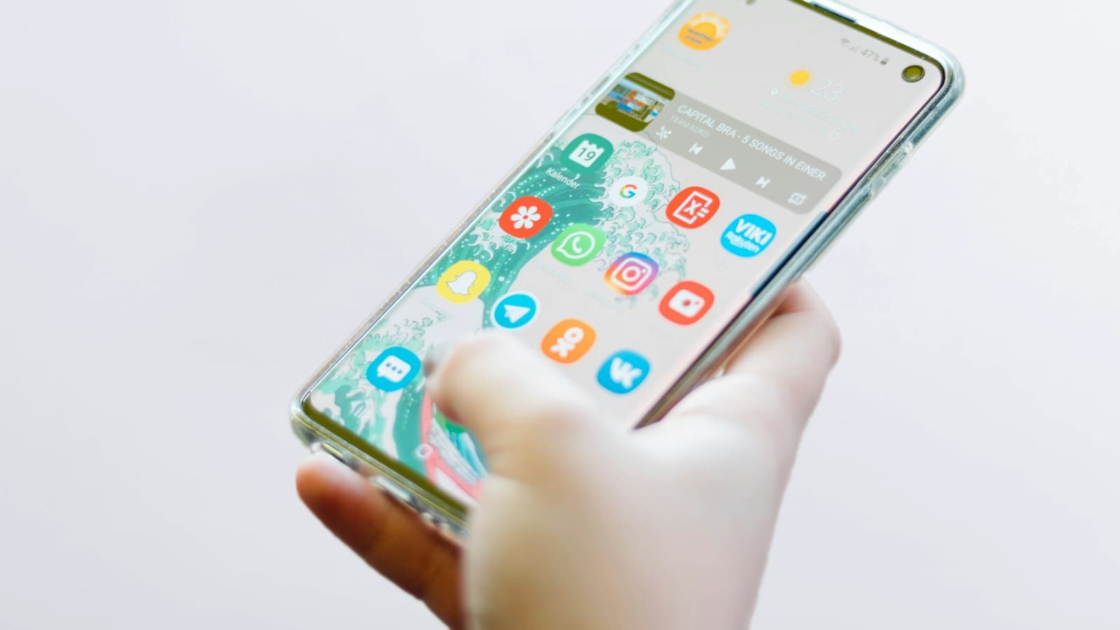Hand holding an Android smartphone showing the home screen