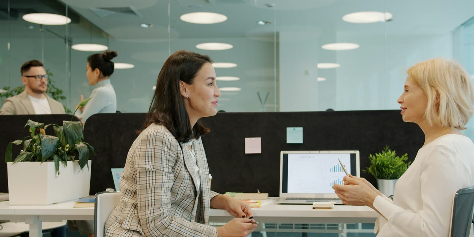 Colleagues talking during a break in a glass-walled office