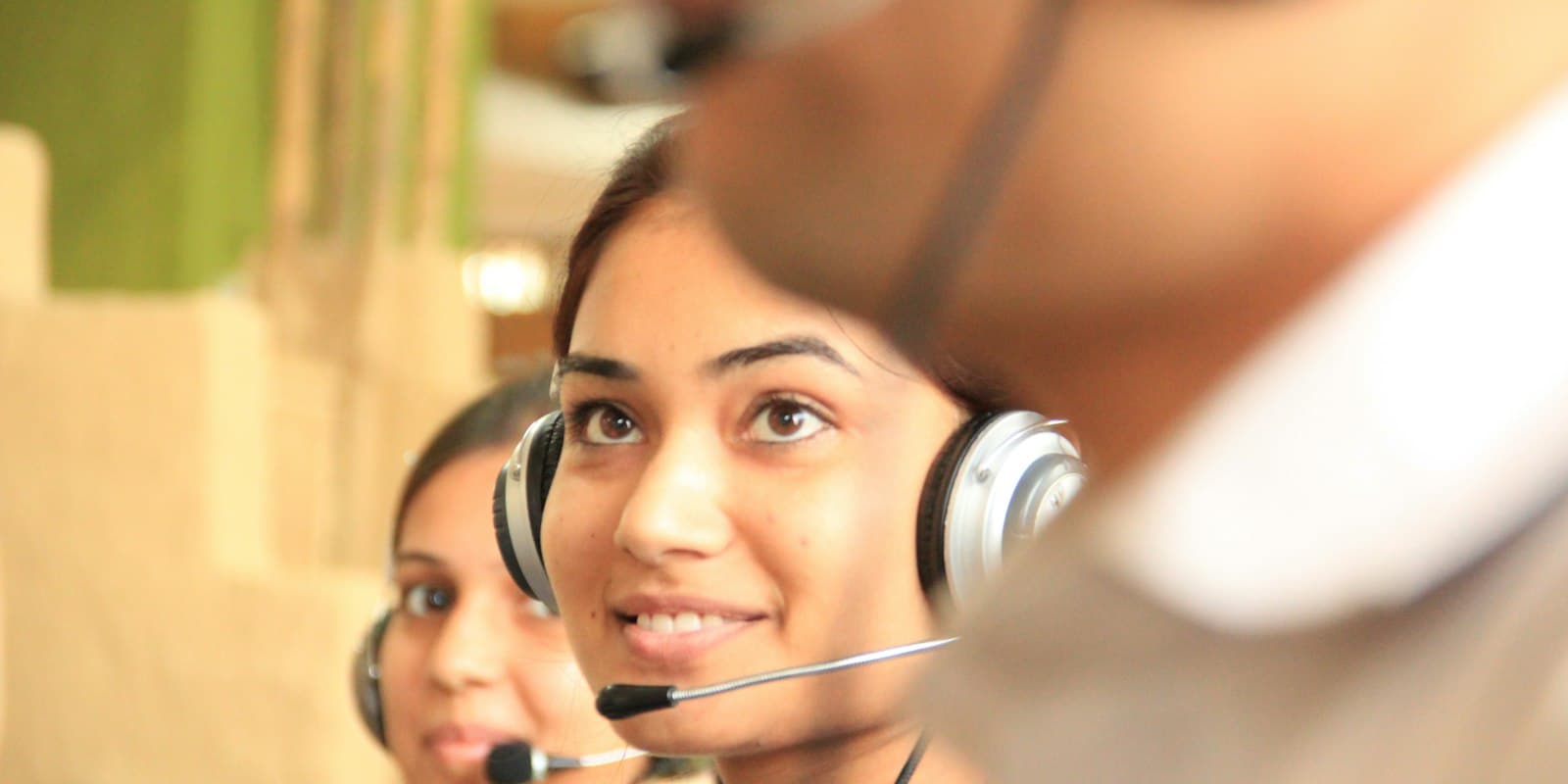 A smiling calling agent wearing a headset in an office