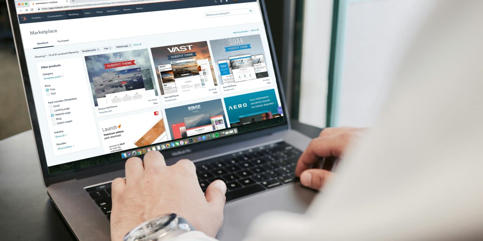 Hands on a laptop showing a web dashboard of listings