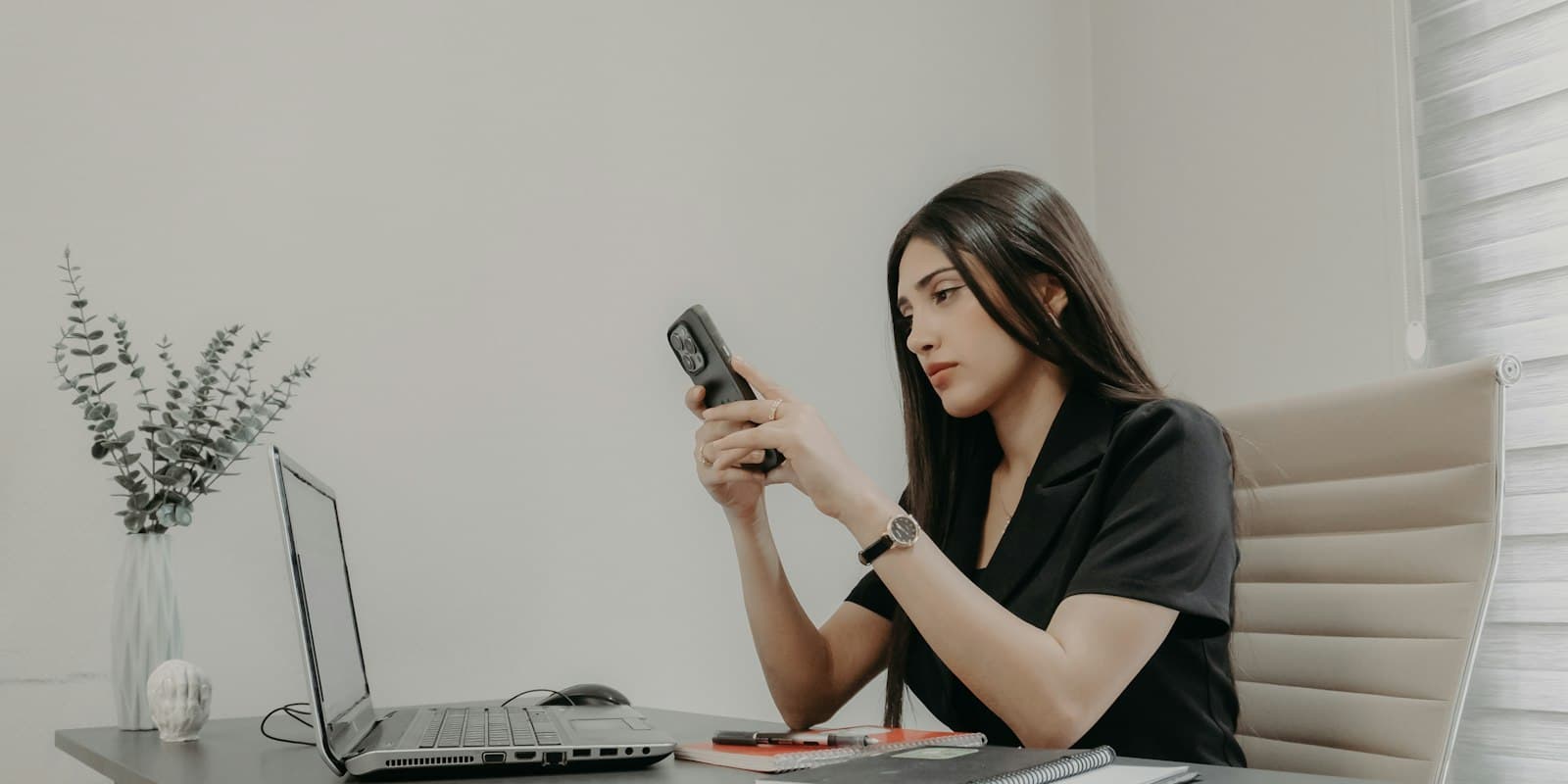 Agent checking follow-up reminders on her phone at her desk