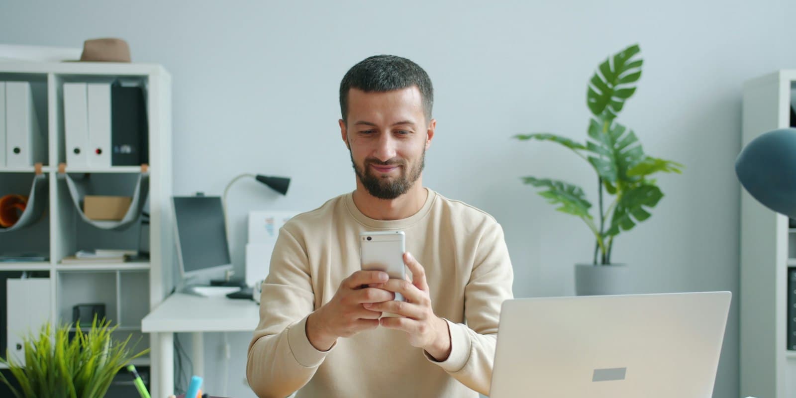Agent smiling at his phone while setting up an app at his desk