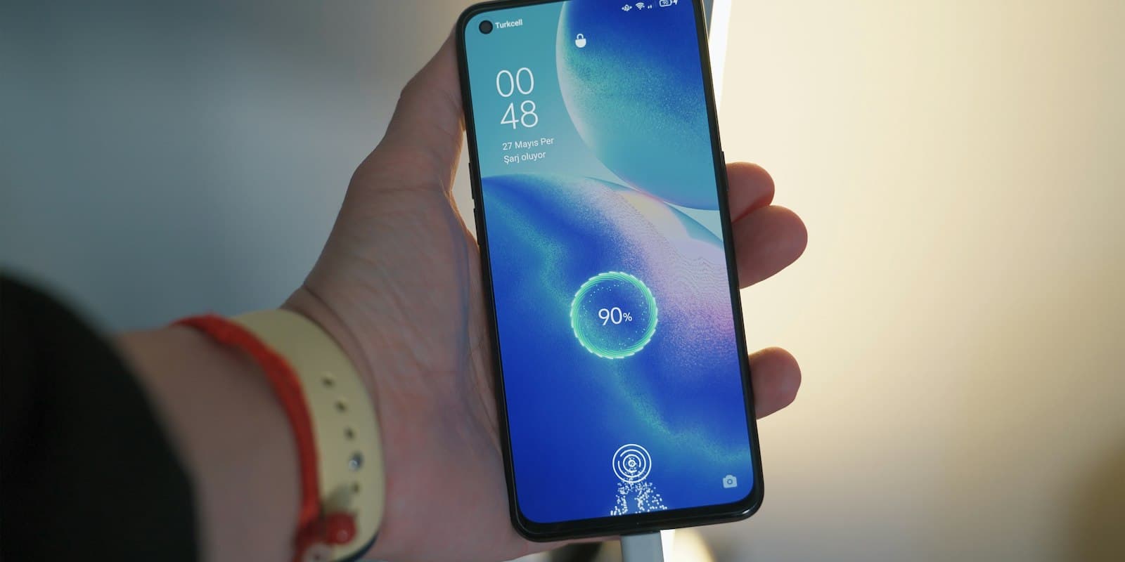 Person holding an Android phone whose lock screen shows the battery charging