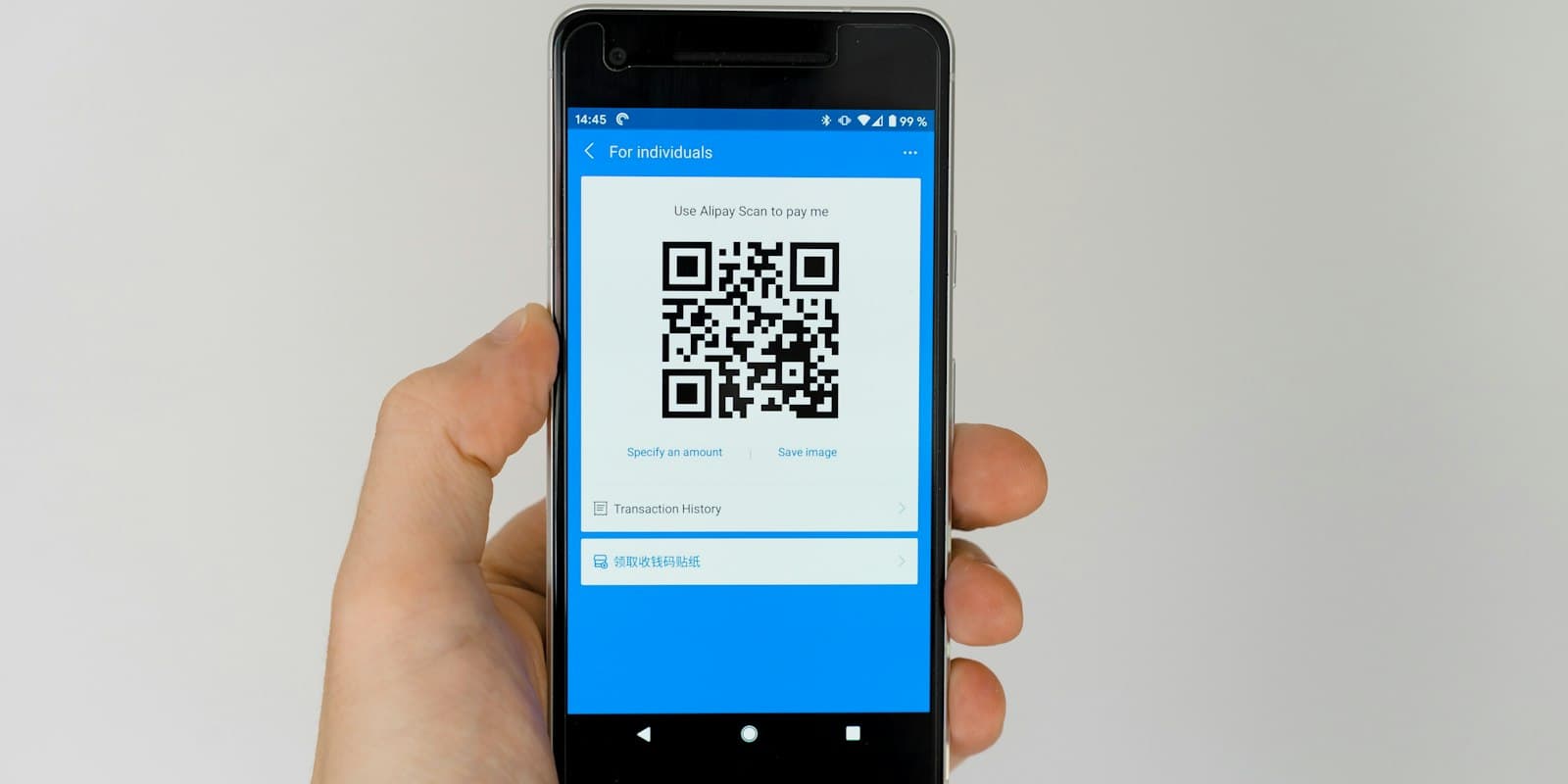 A hand holding an Android phone that shows a QR code