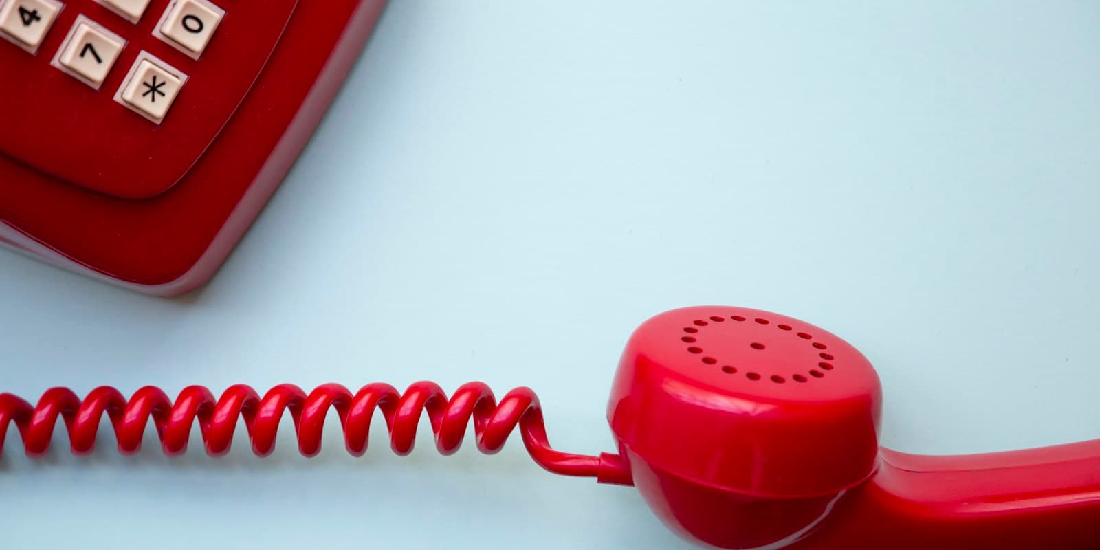 A red telephone with its receiver off the hook