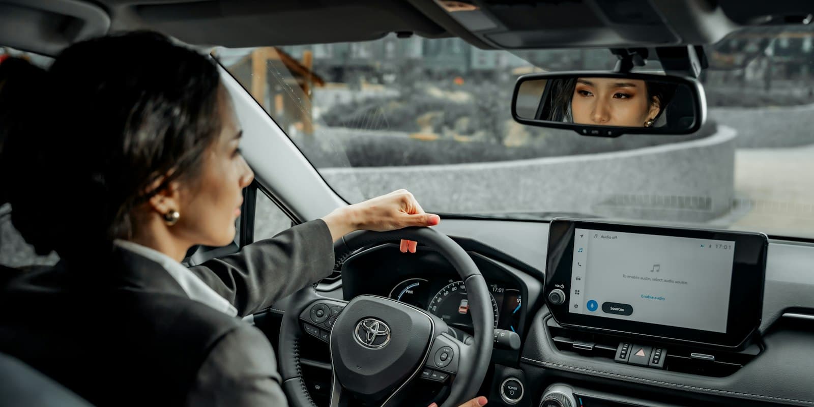 A woman at the wheel of a new car with the dashboard screen lit