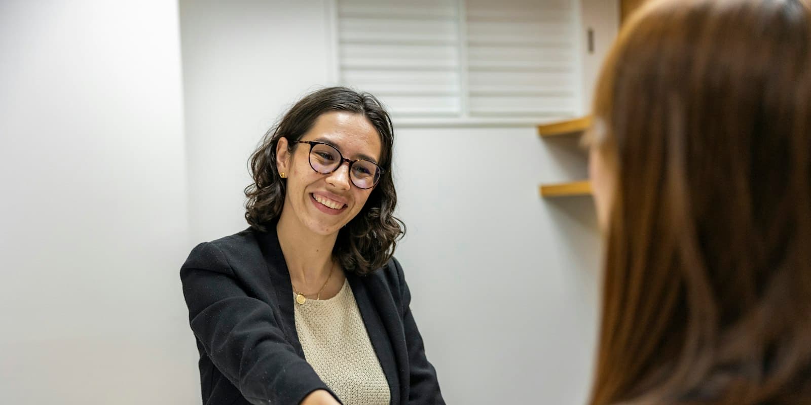 A smiling recruiter greeting a candidate across a desk at an interview