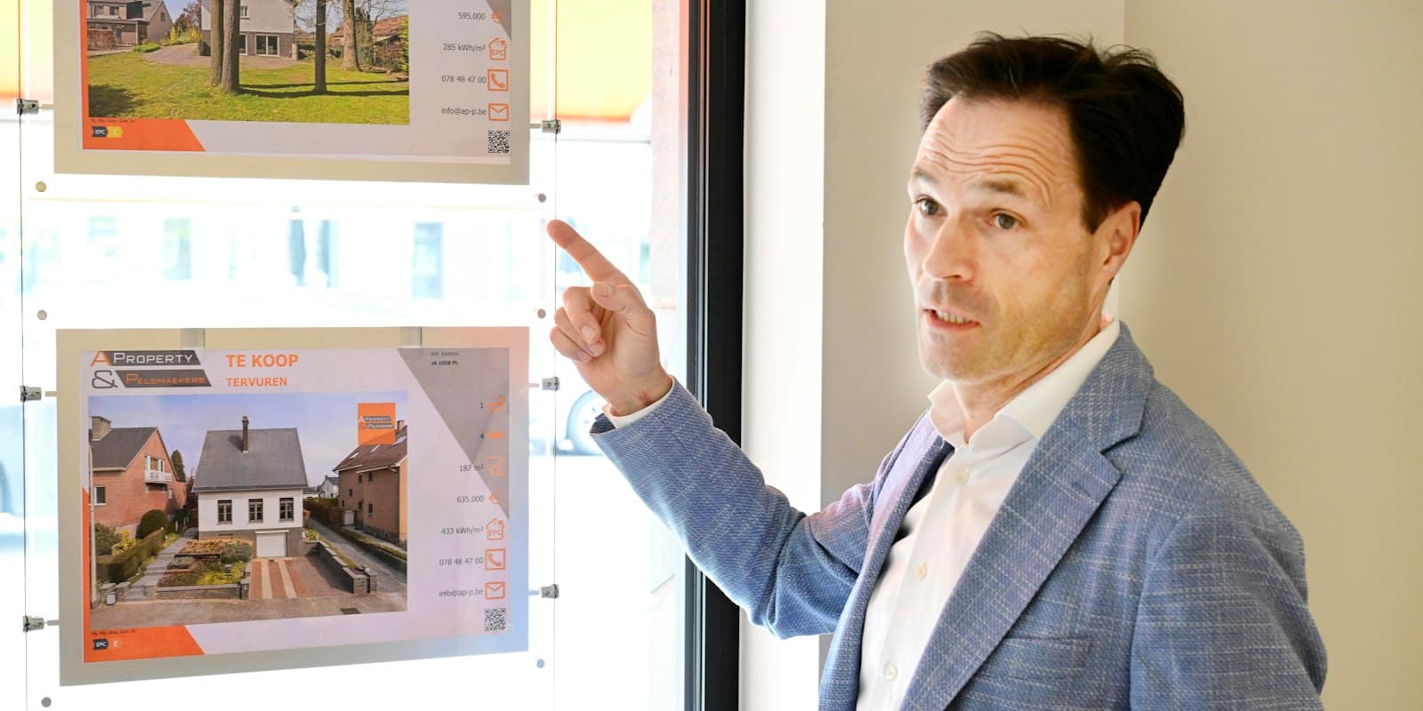 An estate agent pointing to property listings in an office window