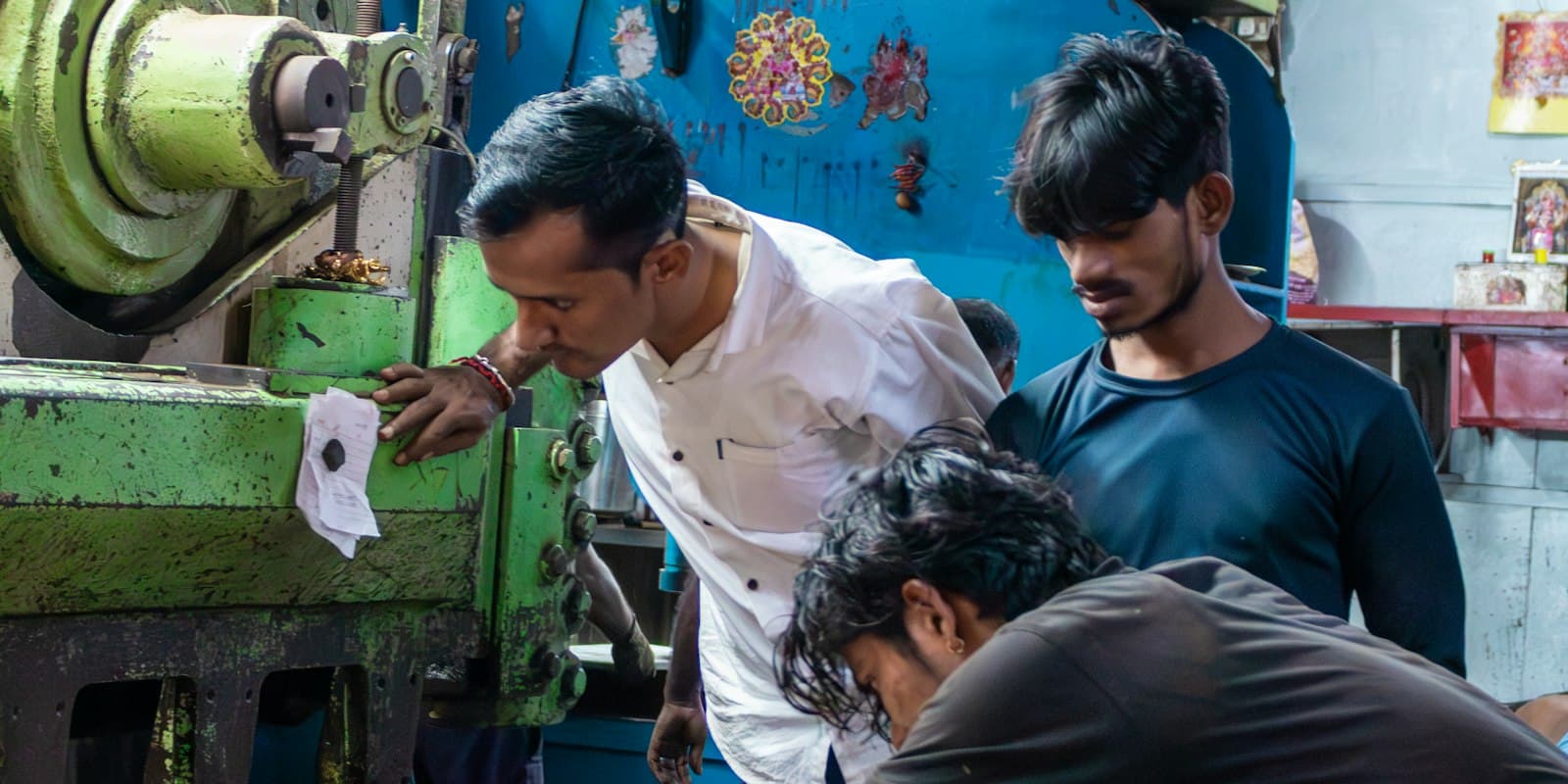 Workers checking a large industrial machine together on a factory floor