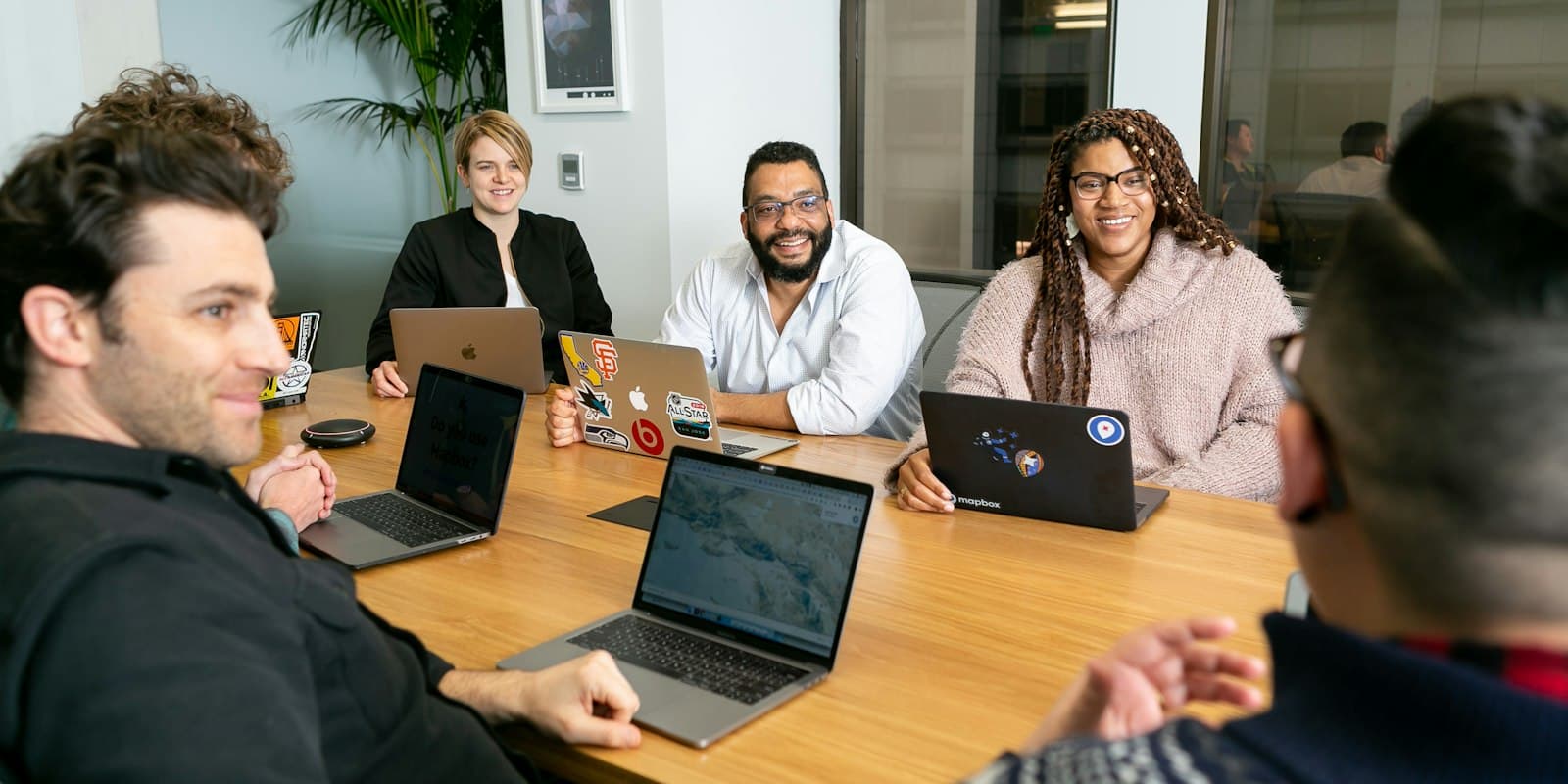 A team of colleagues talking around a table of laptops