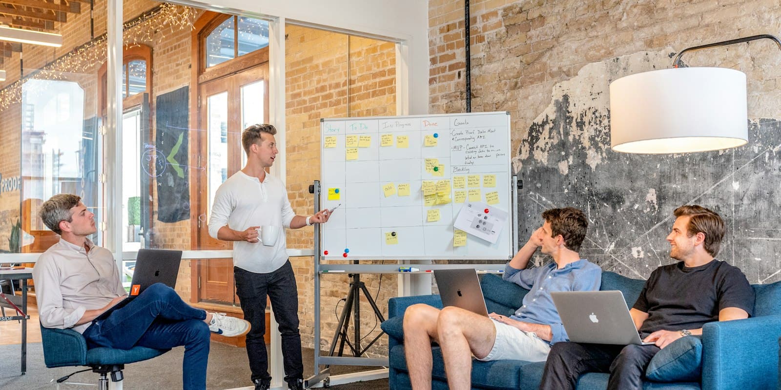 A sales team planning around a whiteboard covered in sticky notes