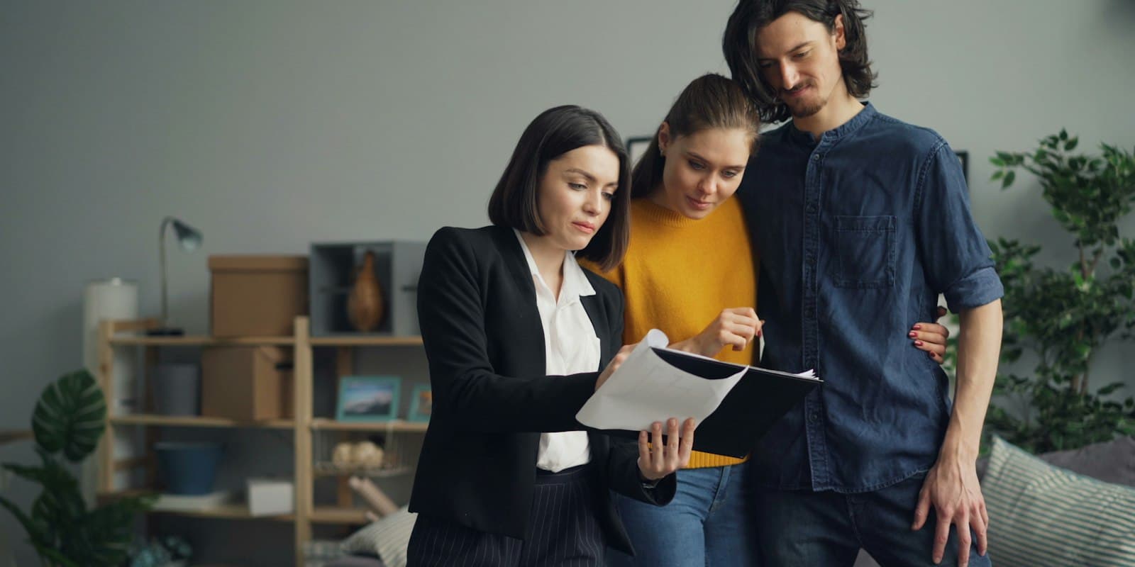 A property agent going through a document with a young couple in a living room