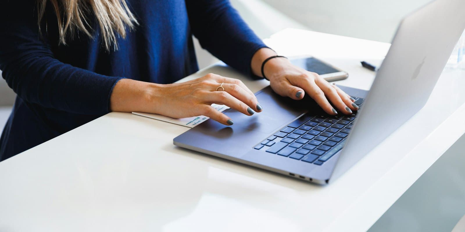 Hands typing on a laptop at a white desk
