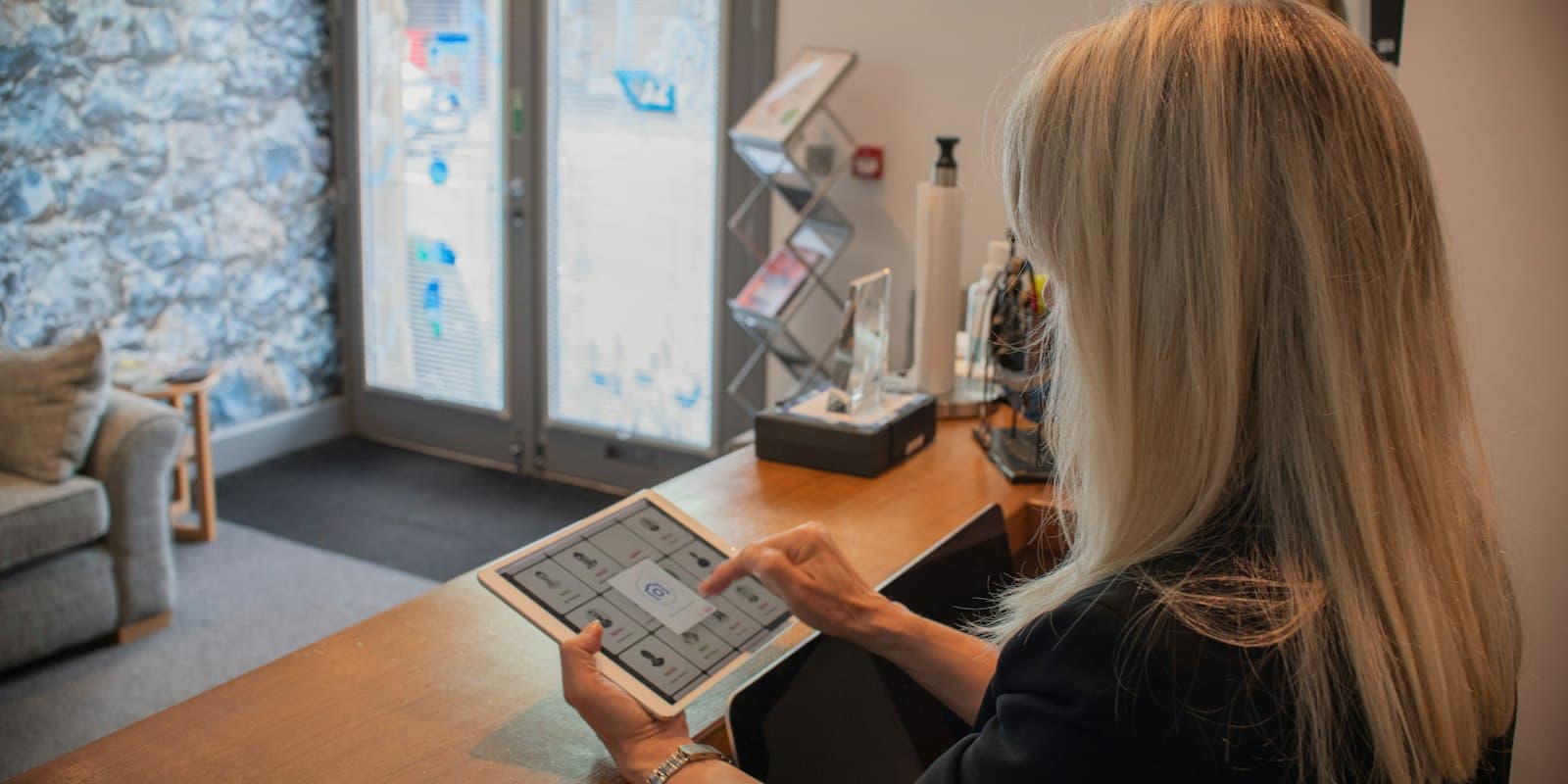 A woman at a reception desk filling in a form on a tablet