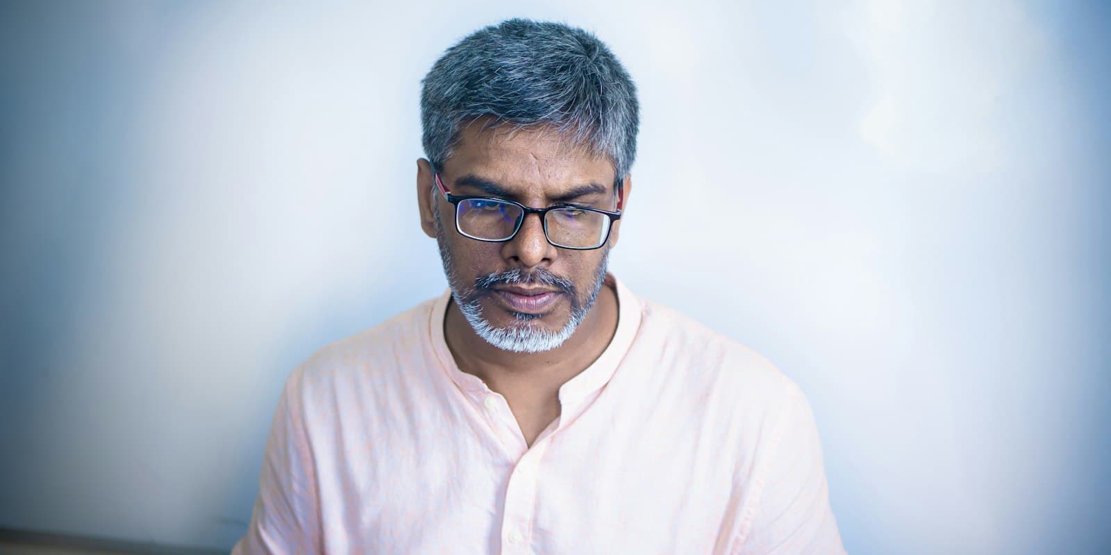 A man in glasses reading something on his laptop