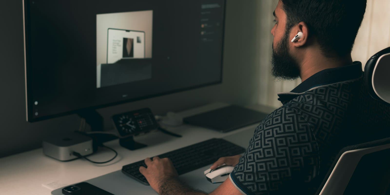 A man working at a desktop computer in a dimly lit office