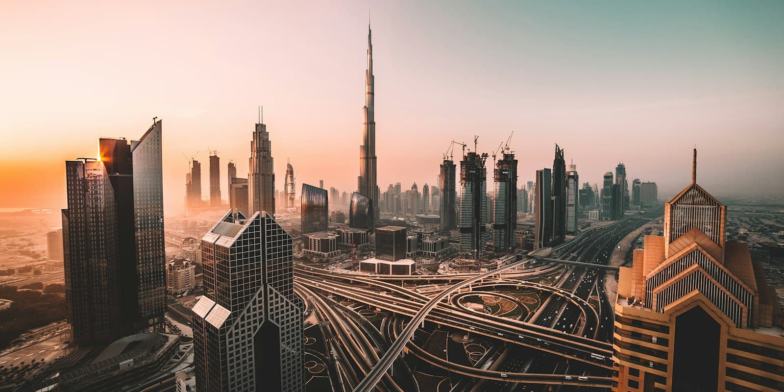 Dubai’s skyline at sunset, with the Burj Khalifa above a multi-level road interchange